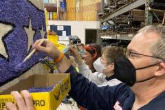 L/R Molly Shock, Patricia A. Kennedy & Erik C. Andersen apply blue statice to the hang glider. --- Photo by F. Hudson Miller